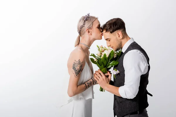 Vue latérale de belle mariée tatouée embrassant beau marié isolé sur blanc — Photo de stock