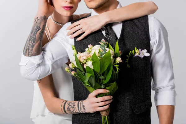 Vista recortada de la novia tatuada abrazando novio aislado en gris - foto de stock