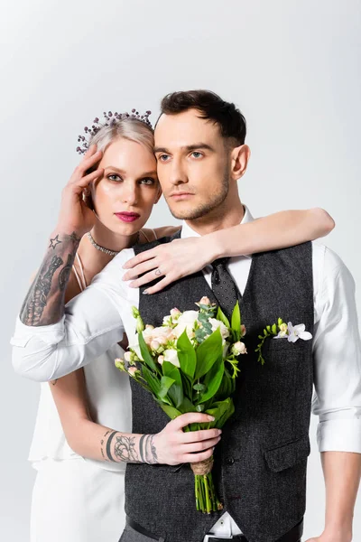 Bella sposa tatuata abbracciando bello sposo isolato su grigio — Foto stock