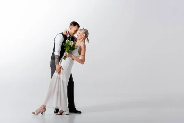 Belle mariée tatouée et beau marié dansant sur blanc — Photo de stock