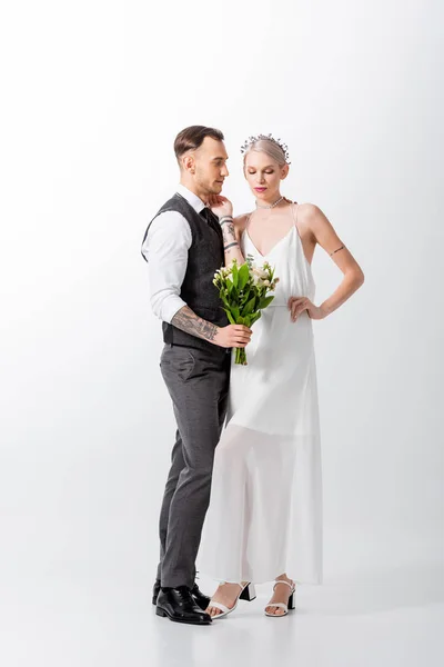 Belle mariée tatouée avec bouquet et beau marié sur blanc — Photo de stock