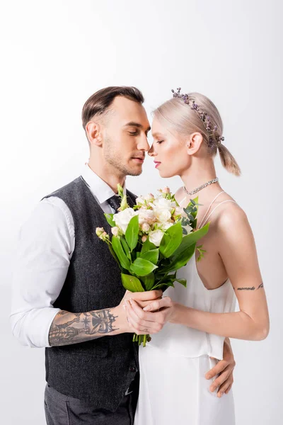 Beautiful tattooed bride and handsome bridegroom standing nose to nose isolated on white — Stock Photo