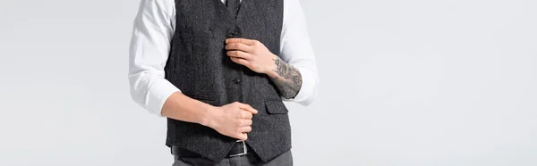 Cropped view of tattooed elegant bridegroom buttoning waistcoat isolated on white, panoramic shot — Stock Photo