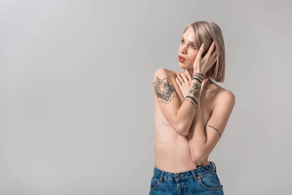 Sexy joven en topless mujer tatuada posando aislado en gris - foto de stock