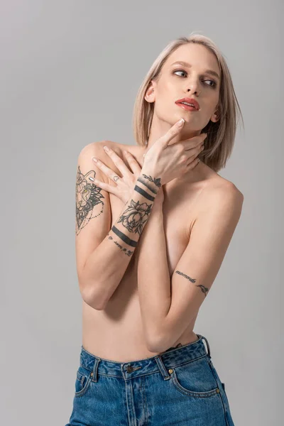 Sexy giovane donna tatuata in topless posa isolata sul grigio — Foto stock