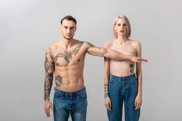 Jeune couple nu tatoué isolé sur gris — Photo de stock