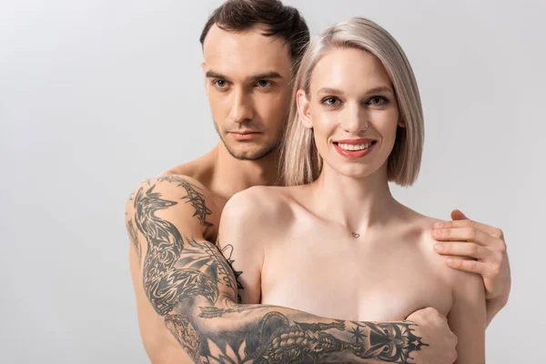 Feliz jovem nu tatuado casal abraço isolado no cinza — Fotografia de Stock