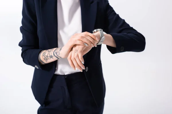 Обрезанный вид успешной молодой татуированной предпринимательницы с наручными часами на руке, изолированными на белом — стоковое фото