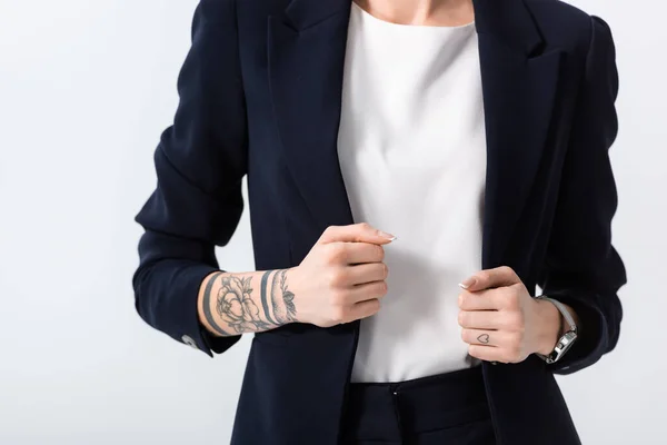 Vista recortada de la exitosa joven mujer de negocios tatuada con las manos en la chaqueta aislada en blanco - foto de stock
