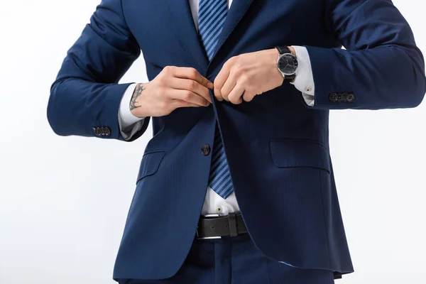 Vue recadrée de succès tatoué jeune homme d'affaires en costume bleu boutonnage blazer isolé sur blanc — Photo de stock