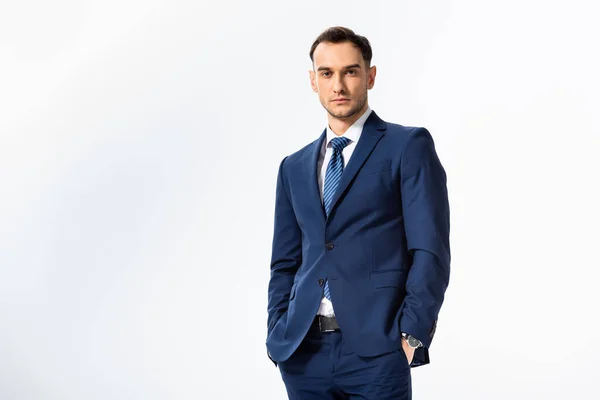 Successful young businessman in blue suit with hands in pockets isolated on white — Stock Photo