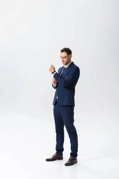 Vista completa del exitoso joven hombre de negocios en traje azul sobre fondo blanco - foto de stock