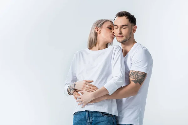 Giovane donna incinta tatuata baciare marito isolato su grigio — Foto stock