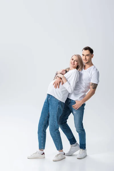 Happy young tattooed pregnant woman with husband on grey — Stock Photo