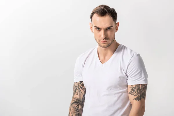 Серьезный красивый молодой татуированный мужчина изолирован на белом — стоковое фото