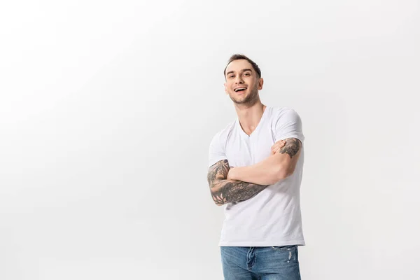 Feliz bonito jovem tatuado homem com cruzados braços isolado no branco — Fotografia de Stock