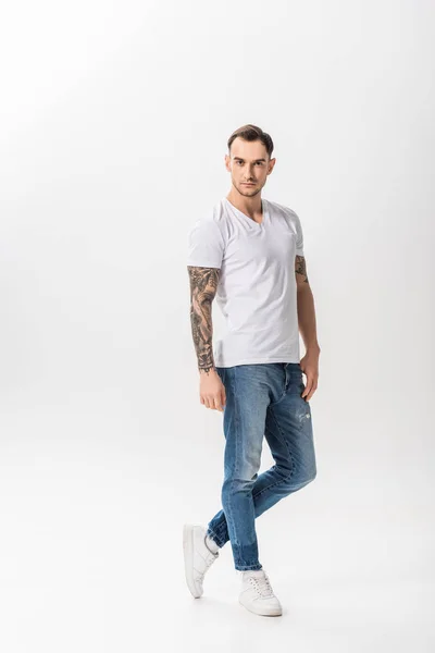 Vue pleine longueur de beau jeune homme tatoué posant isolé sur blanc — Photo de stock