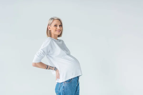 Seitenansicht der glücklichen jungen tätowierten Schwangeren isoliert auf grau — Stockfoto