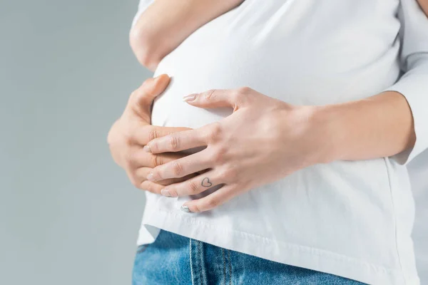 Обрізаний вид на молоду татуйовану вагітну жінку з хлопцем ізольовано на сірому — стокове фото
