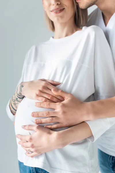 Vue recadrée de jeune femme enceinte tatouée avec petit ami isolé sur gris — Photo de stock