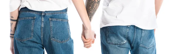 Задний вид молодой татуированной пары, держащейся за руки изолированные на белом, панорамный снимок — стоковое фото