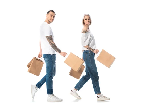 Junges tätowiertes Paar spaziert mit Einkaufstüten auf weißem Grund — Stockfoto