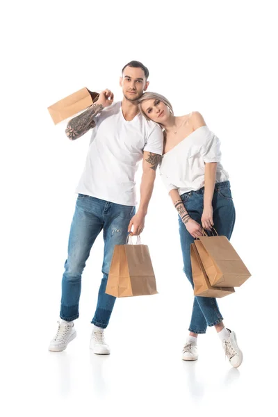 Jeune couple tatoué avec des sacs à provisions sur blanc — Photo de stock