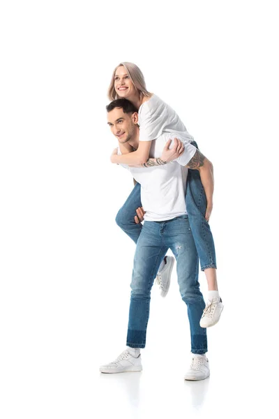 Feliz joven tatuado pareja piggybacking aislado en blanco - foto de stock