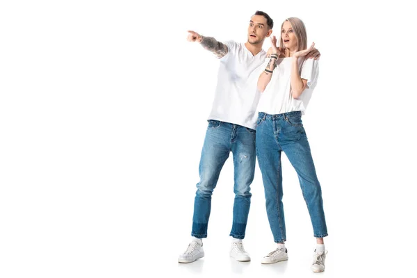 Choqué jeune couple tatoué pointant avec doigt loin isolé sur blanc — Photo de stock