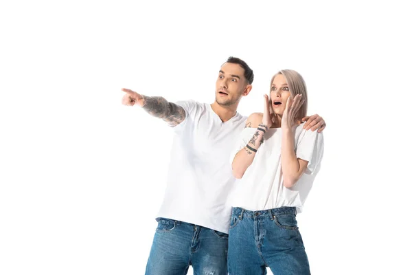 Shocked young tattooed couple pointing with finger away isolated on white — Stock Photo