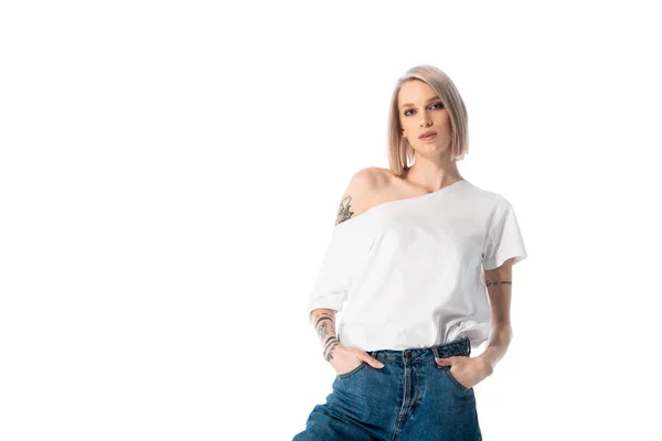 Atraente jovem tatuado menina posando com as mãos em bolsos isolados no branco — Fotografia de Stock