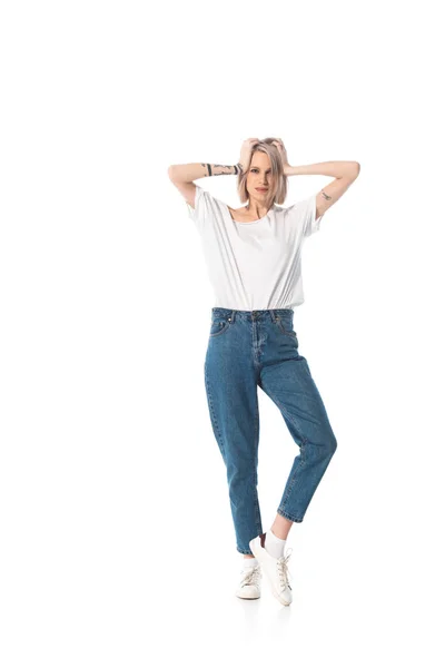 Joven chica tatuada posando con las manos en la cabeza aisladas en blanco — Stock Photo