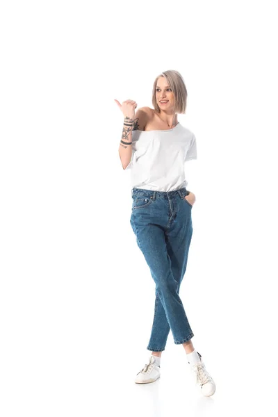 Sonriente joven tatuada chica señalando con el dedo de distancia aislado en blanco - foto de stock