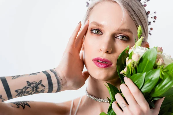 Портрет красивой татуированной невесты, позирующей с цветочным букетом, изолированным на белом — стоковое фото