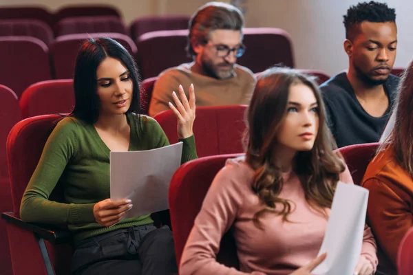 Multiethnic actors and actresses reading scripts on seats in theatre — Stock Photo