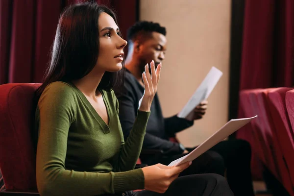 Jeune acteur et actrice multiculturelle lisant des scénarios dans le théâtre — Photo de stock