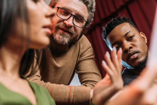 Multicultural actor and actress reading screenplay with mature theater director — Stock Photo