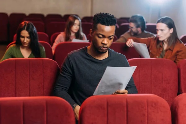 Ator americano africano lendo roteiro em assentos no teatro — Fotografia de Stock