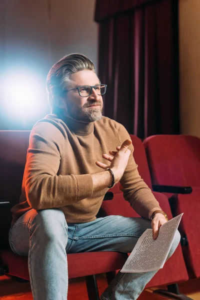 Emotional stage director with scenario on seats in theater with backlight — Stock Photo