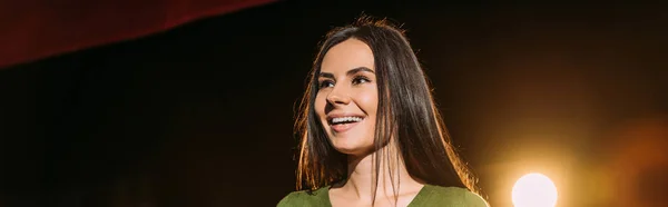 Tiro panorâmico da bela atriz sorridente que executa o papel no preto — Fotografia de Stock