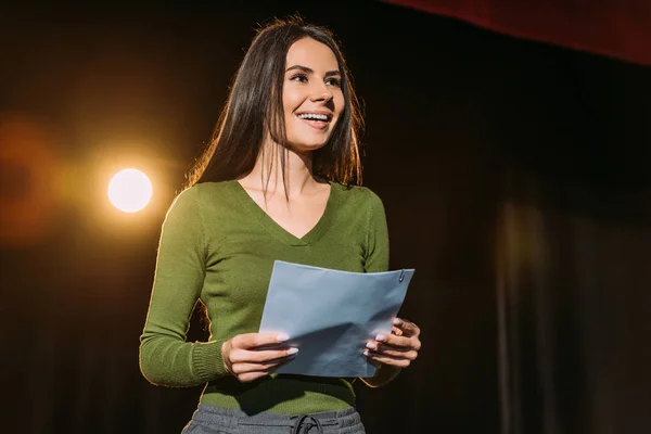 Cheerful actress performing role with screenplay on stage in theatre — Stock Photo