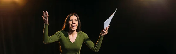 Panoramic shot of attractive emotional actress performing role on black — Stock Photo