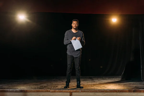 African american actor holding scenario and standing on stage during rehearse — Stock Photo