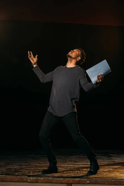 African american actor holding scenario on stage during rehearse — Stock Photo