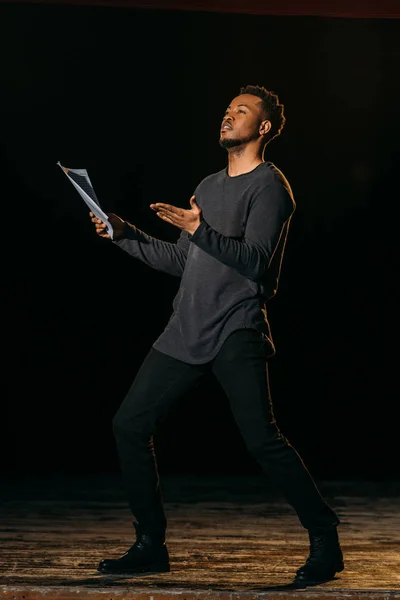 Afrikanisch-amerikanischer Schauspieler hält Szenario und steht auf der Bühne während der Theaterprobe — Stockfoto