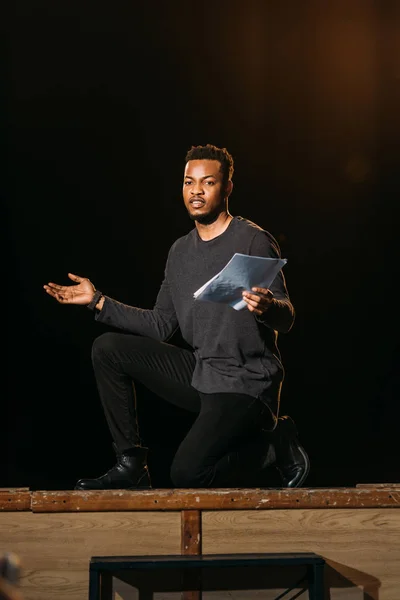 African american actor holding scenario on stage during rehearse — Stock Photo