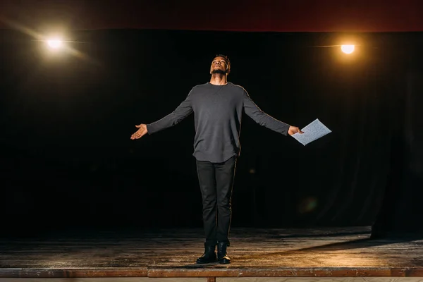 Acteur afro-américain tenant scénario et debout sur scène pendant la répétition — Photo de stock