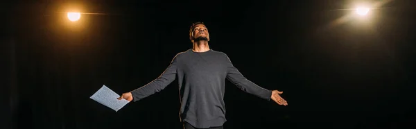 Panoramic shot of african american actor holding scenario and standing on stage during rehearse — Stock Photo