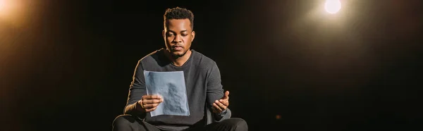 Панорамний епізод афроамериканського актора, який проводить сценарій на сцені під час репетиції — стокове фото