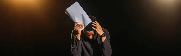 Panoramic shot of emotional african american actor holding scenario on stage during rehearse — Stock Photo